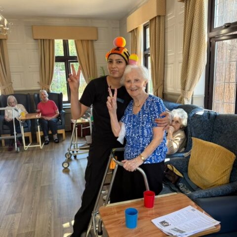Resident and care team member smiling together during an activity in the lounge