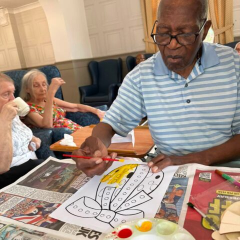 Resident painting a yellow butterfly during an arts and crafts activity