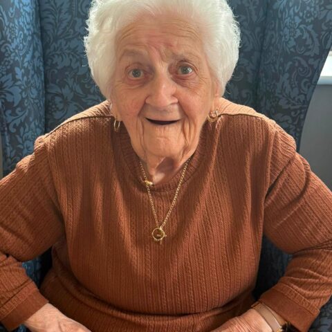 Smiling resident seated comfortably in the Nightingale Care Home lounge