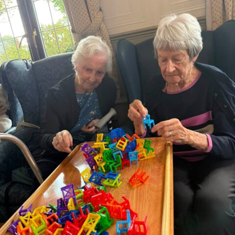 Two residents taking part in a colourful chair stacking tabletop game