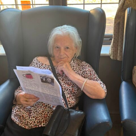 Resident reading the Nightingale newsletter while seated in the lounge