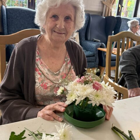 Resident creating a flower arrangement with white and pink flowers