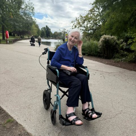 Resident seated by the lake during a relaxing park outing