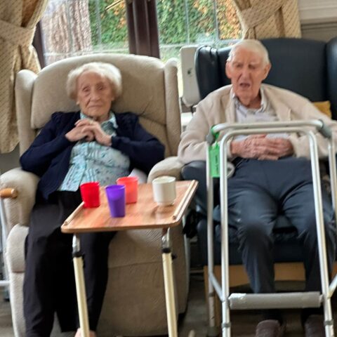 Two residents relaxing together in the care home lounge