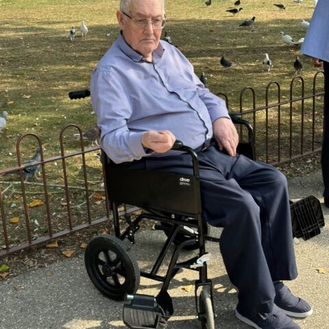 Resident seated outdoors feeding birds during a park outing