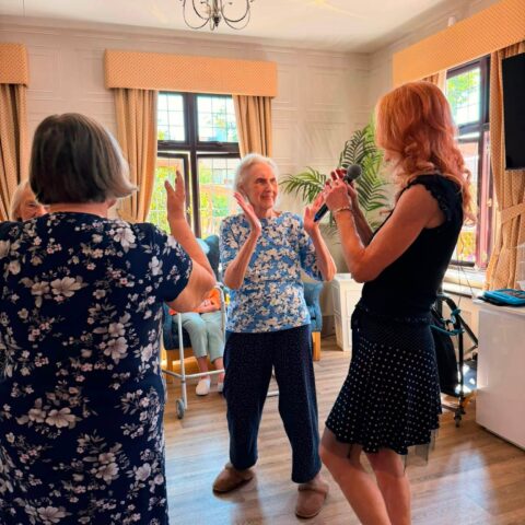 Residents dancing and clapping during live music entertainment in the care home