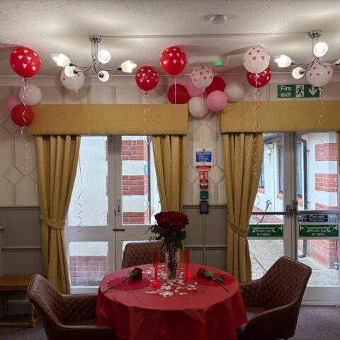Dining area decorated with balloons, hearts and a Happy Anniversary banner at Nightingale Care Home