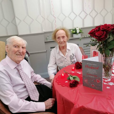 Couple seated at a table decorated with rose petals and an anniversary card