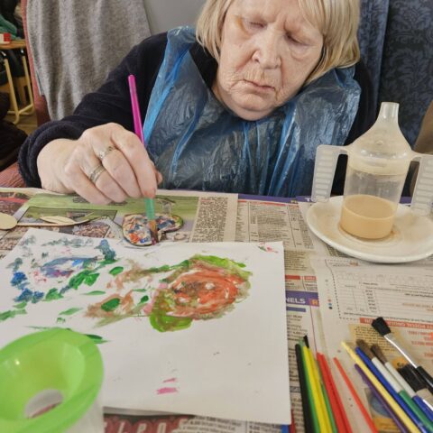 Resident painting colourful artwork during an activity at Nightingale Care Home
