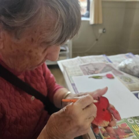 Resident carefully painting a craft design at Nightingale Care Home