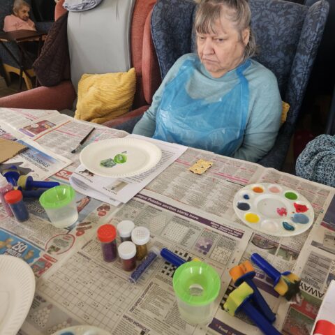 Resident seated with painting and craft materials at Nightingale Care Home
