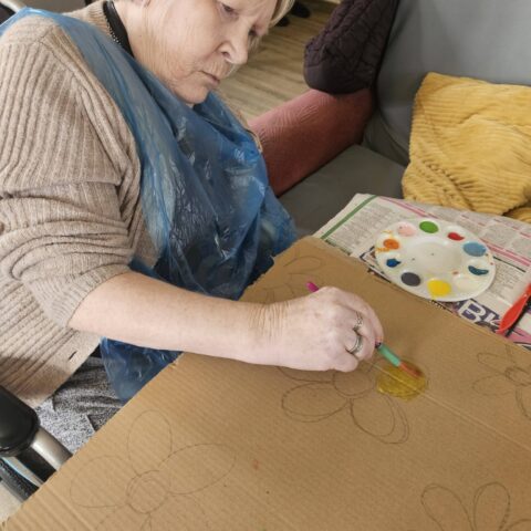 Resident using green paint during an arts and crafts activity at Nightingale Care Home