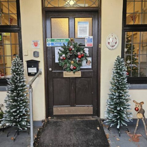 Care home entrance decorated with wreaths and two small Christmas trees