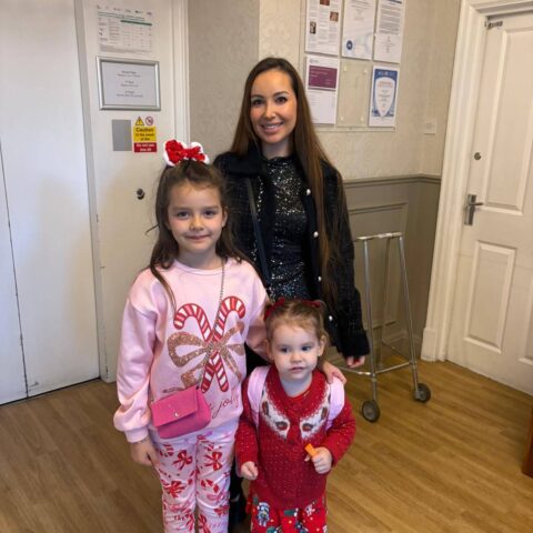 Smiling adult and two children wearing festive clothing in the care home