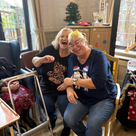Resident and visitor holding hands while dancing near the Christmas tree