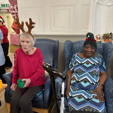 Two residents seated together wearing festive reindeer antlers