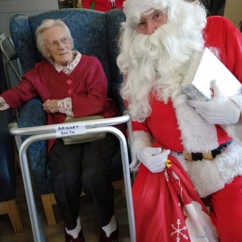Resident seated beside Santa with a red Christmas gift sack