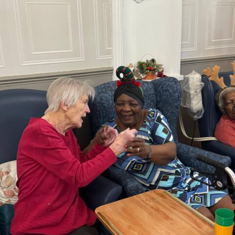 Two residents seated together and interacting during a festive lounge activity