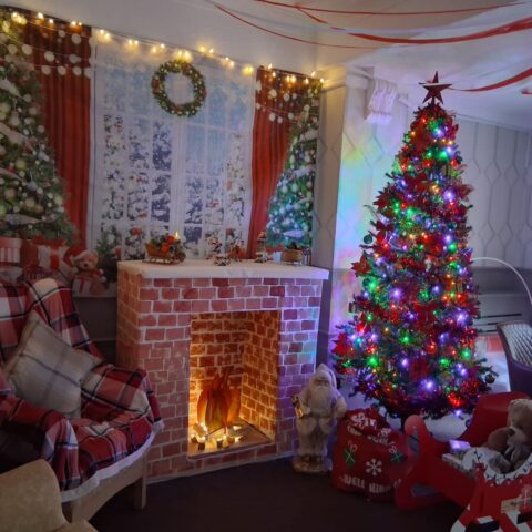Christmas tree and glowing fireplace surrounded by festive decorations and gifts