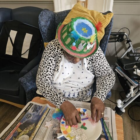 Resident holding a decorated Easter bonnet in front of their face