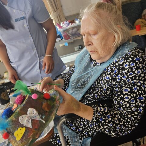 Resident concentrating while adding colourful decorations to a handmade Easter bonnet