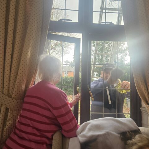Resident standing by a window and gently stroking a visiting dog