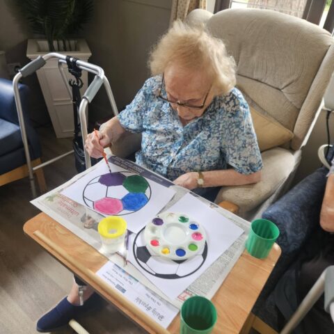 Resident painting a football picture during an arts activity