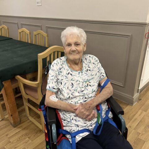 Smiling resident seated comfortably near dining tables