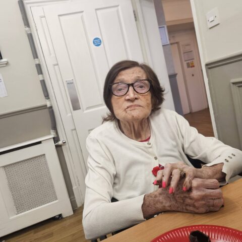 Resident seated at a table beside a chocolate cupcake during the Valentine’s event