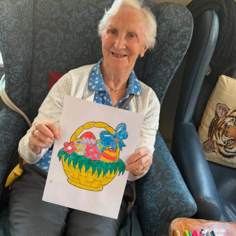 Resident holding a colourful Easter basket picture completed during a craft activity