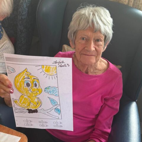 Resident proudly holding up her completed colourful duck picture