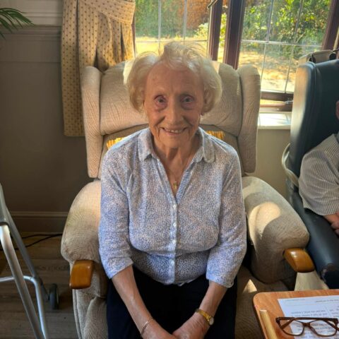 Smiling resident sitting in a comfortable chair beside the garden window