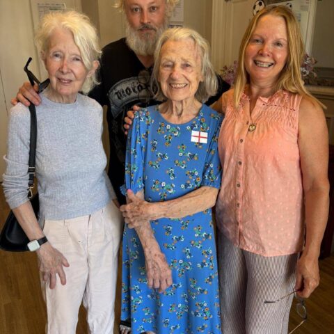 Group of residents and family posing indoors with England flag decorations during the World Cup celebration.