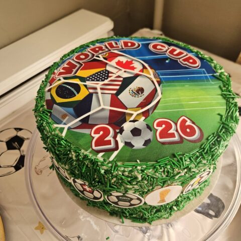 A World Cup 2026 themed cake decorated with flags and green sprinkles.